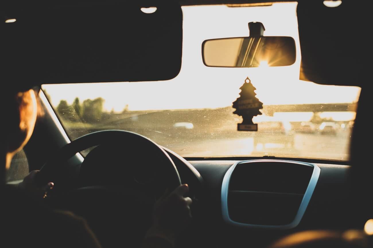 View from driver seat of a car looking forward toward a sunrise