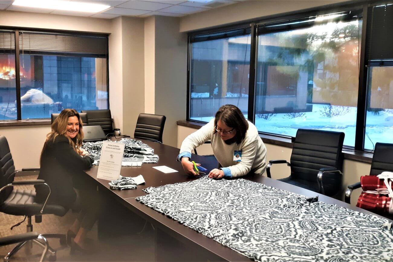 Twin Cities Pain Clinic team making holiday tie blankets in conference room
