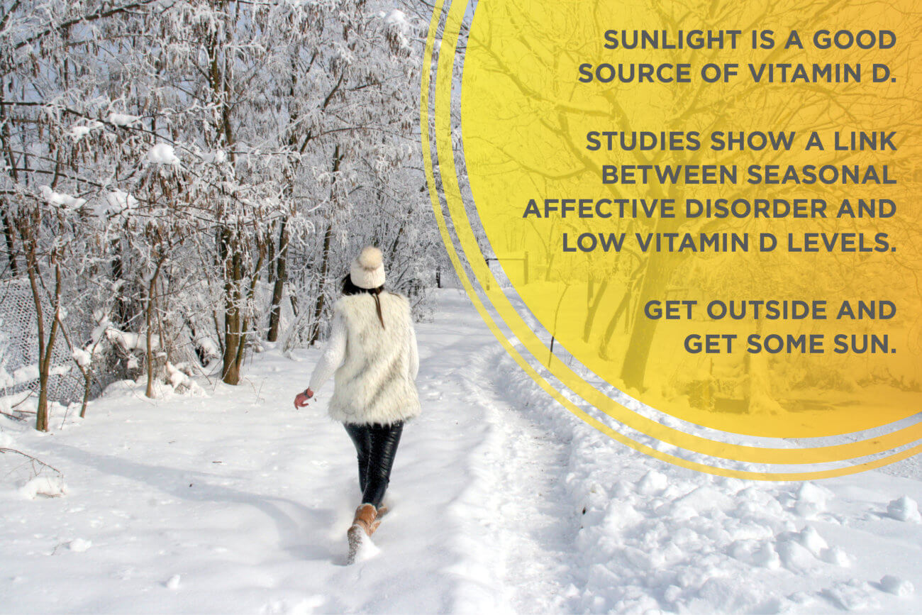 Fact about vitamin D and cunlight in front of a woman walking through a snowy forest