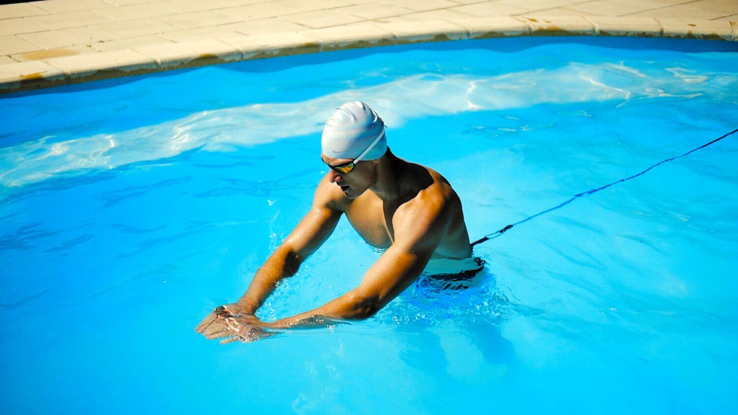 Man in a swim cap performing water aerobics in a pool