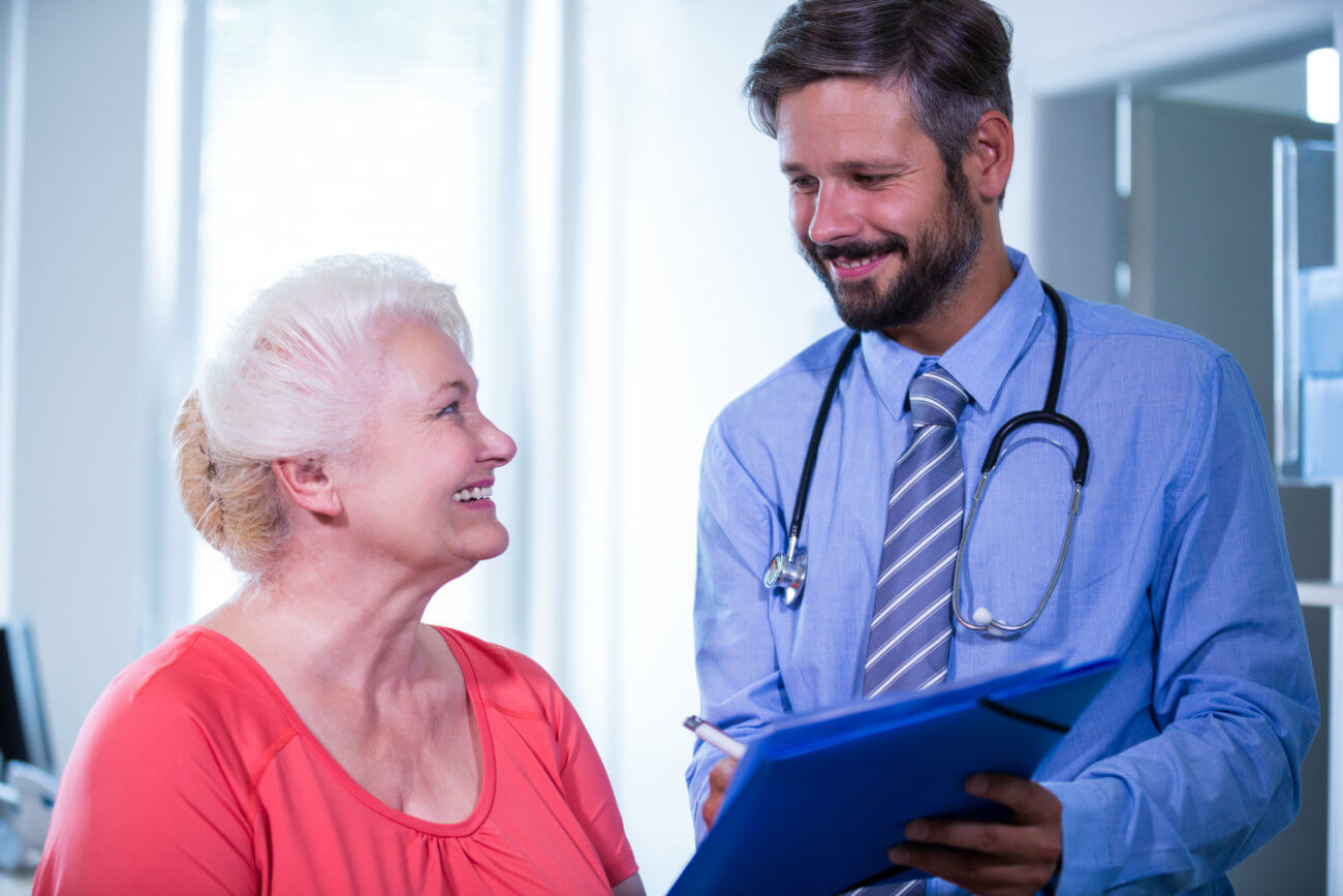 Young male doctor reviewing medical chart with senior female