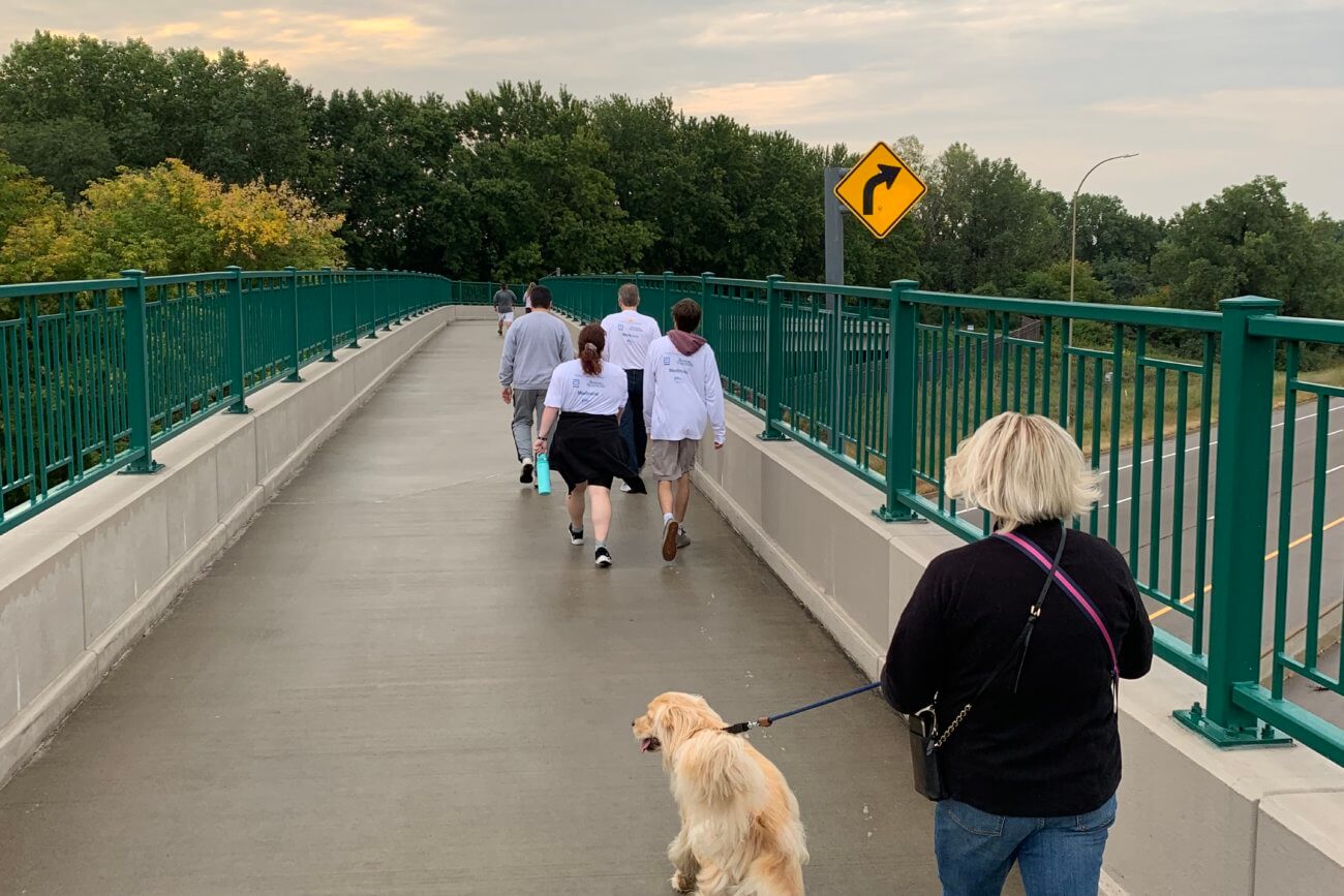 Participants of the 2022 Twin Cities Pain Clinic Pain Awareness 5k Crossing the Highway 100 Pedestrian Bridge