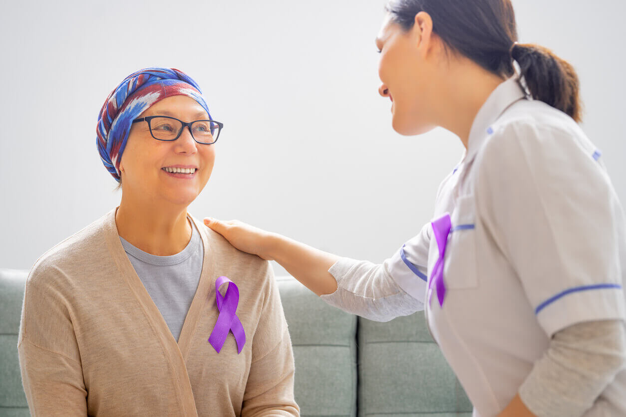 Healthcare provider with her hand on the shoulder of a smiling cancer patient